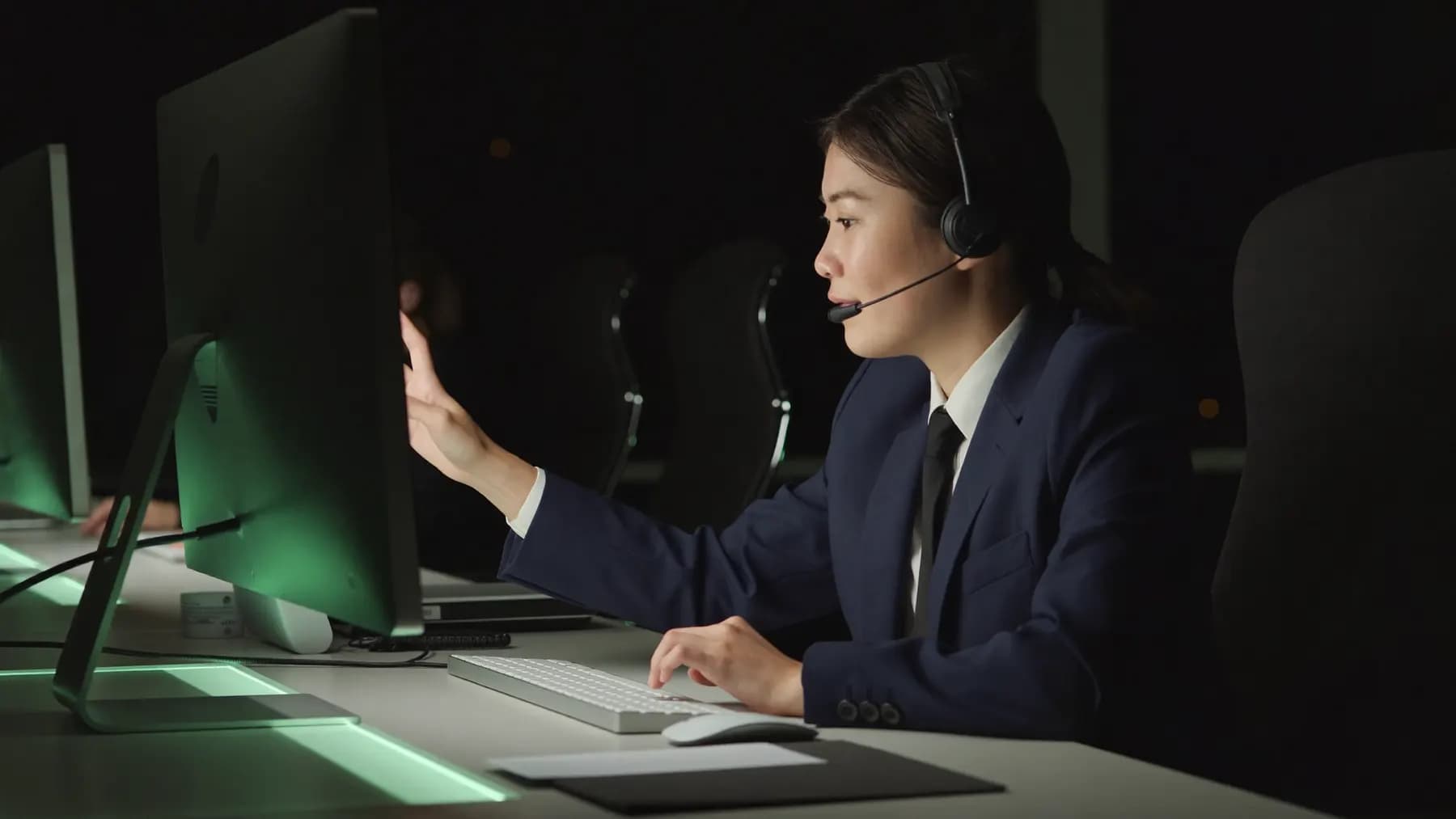 Een verkoper met headset achter een beeldscherm, laat op de avond.